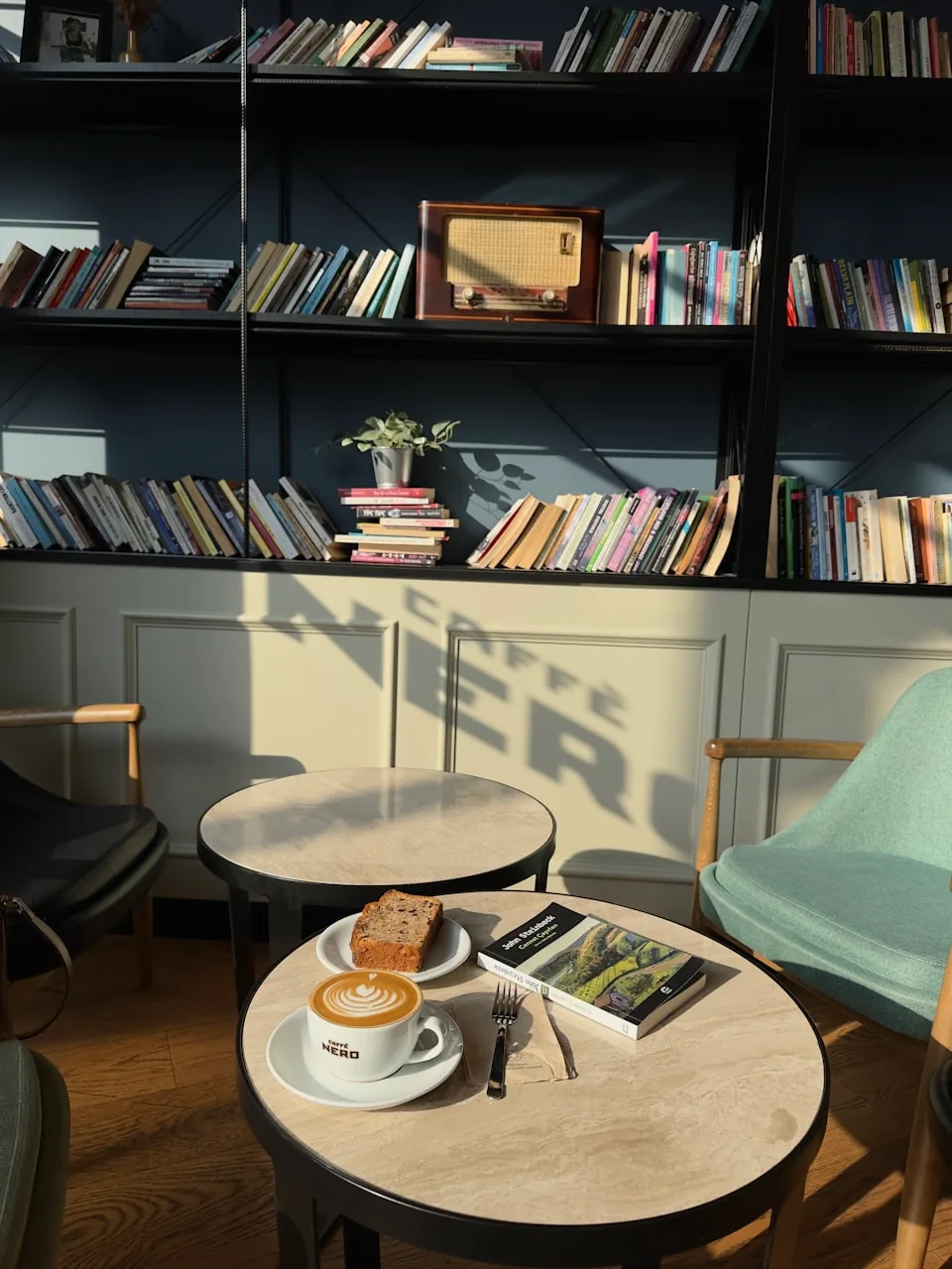 Des livres accompagnent une tasse de café et une part de gâteau.